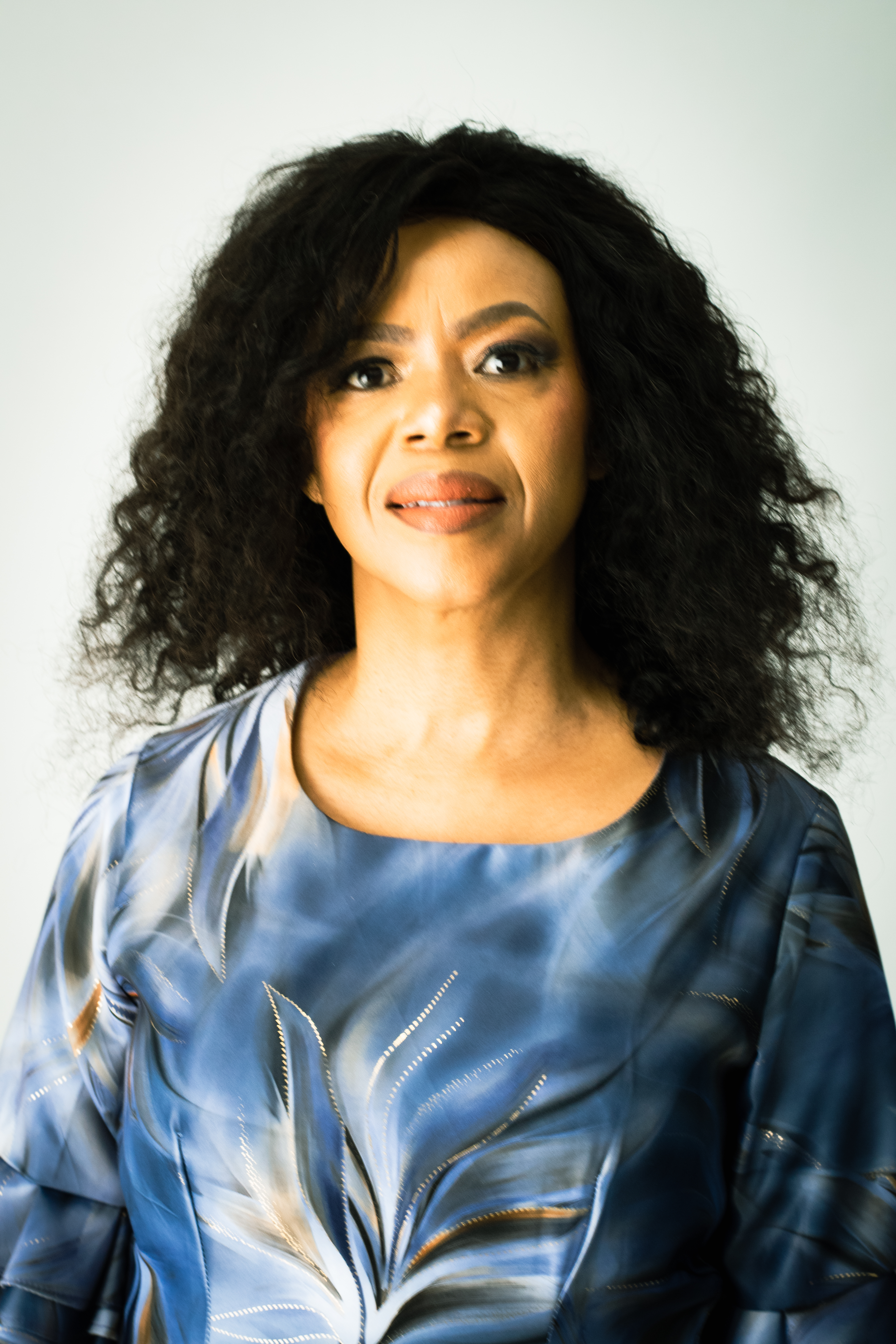 Close-up studio portrait of a woman wearing a blue patterned dress