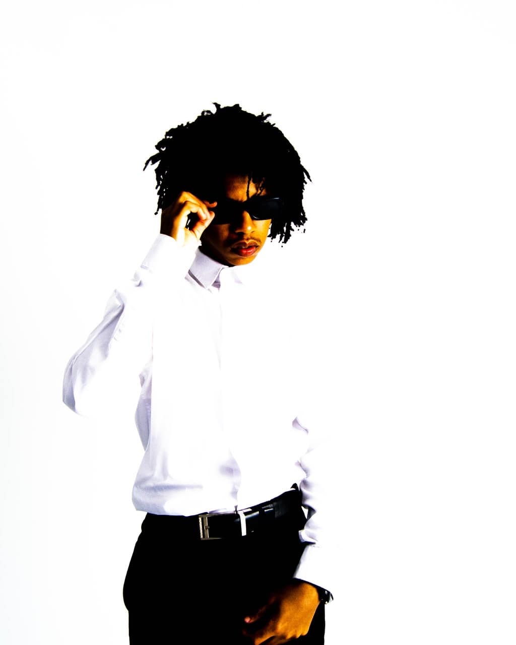 Man wearing sunglasses and a white shirt against a white studio backdrop
