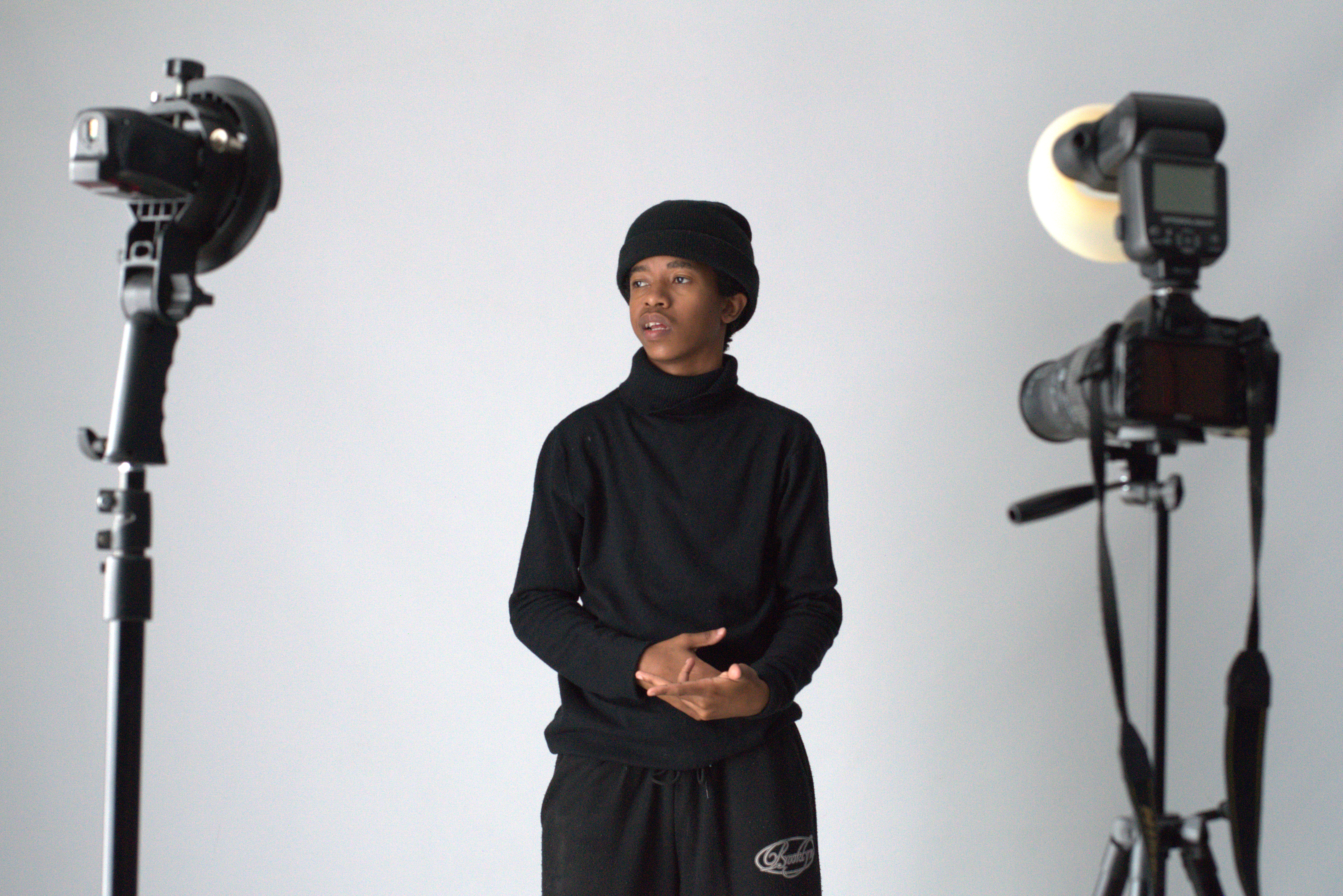 Studio portrait session framed between photography lights and camera equipment